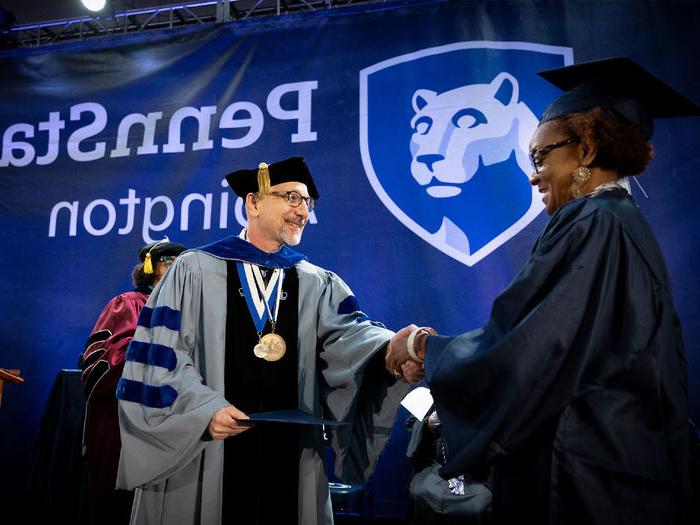Interim Chancellor Andrew August presents a Penn State Abington student with her diploma